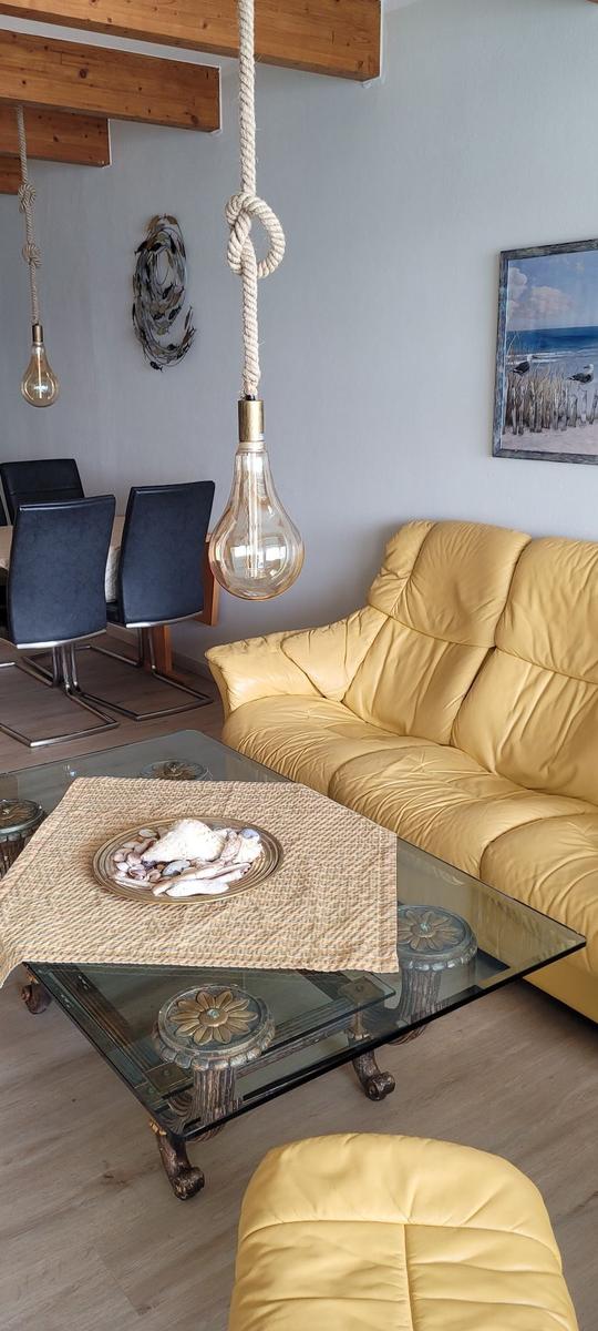 Gelber Ledersofa, Glas-Tisch mit Schale, hängende Lampe und Wandbild
