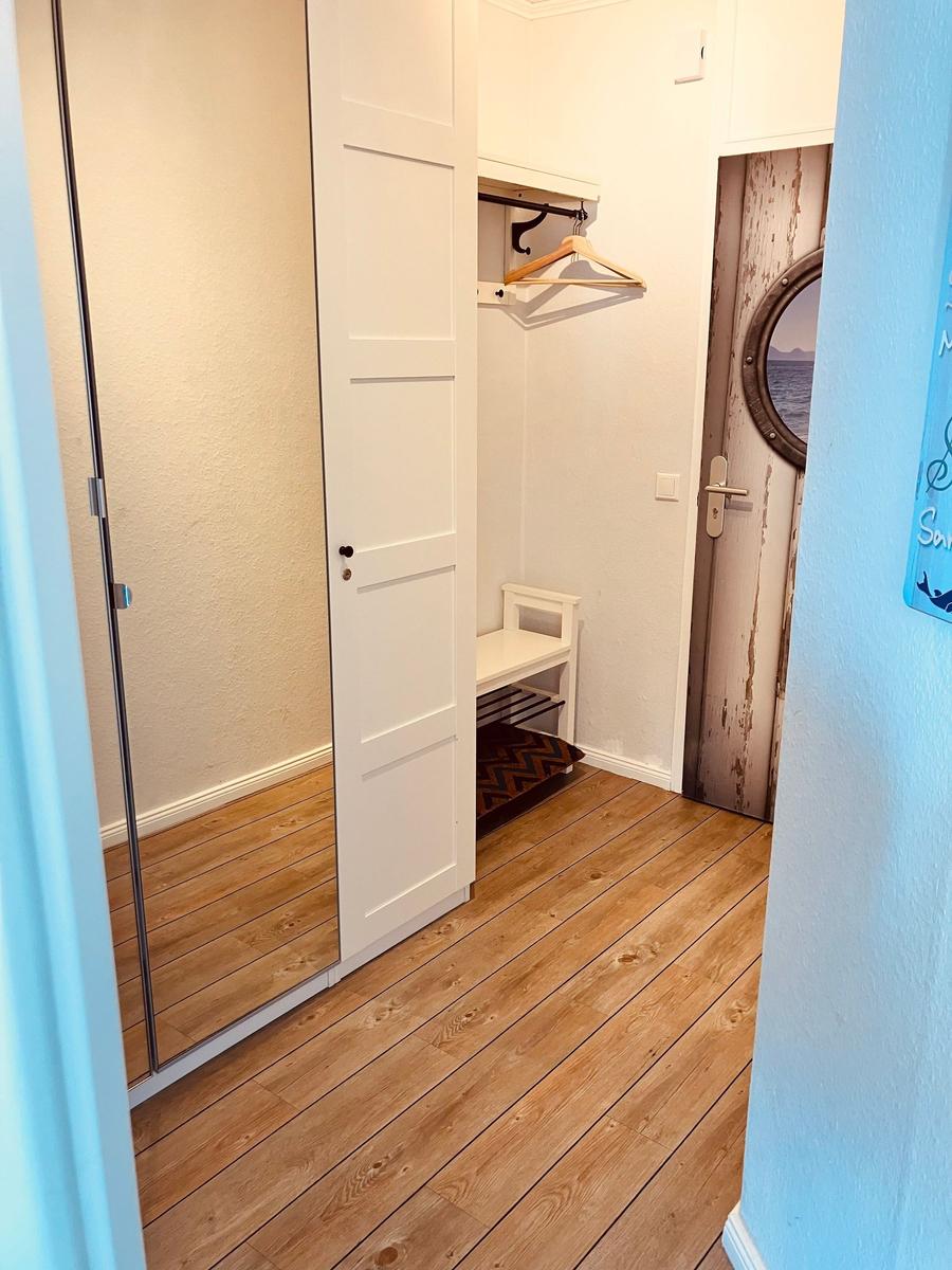 Schlafzimmer mit Kleiderschrank, Sitzbank und Tür mit runden Fenster.
