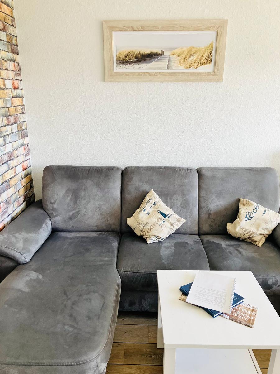 Graße Couch mit Kissen und Tisch im Wohnzimmer mit Wandbild und Holzboden.