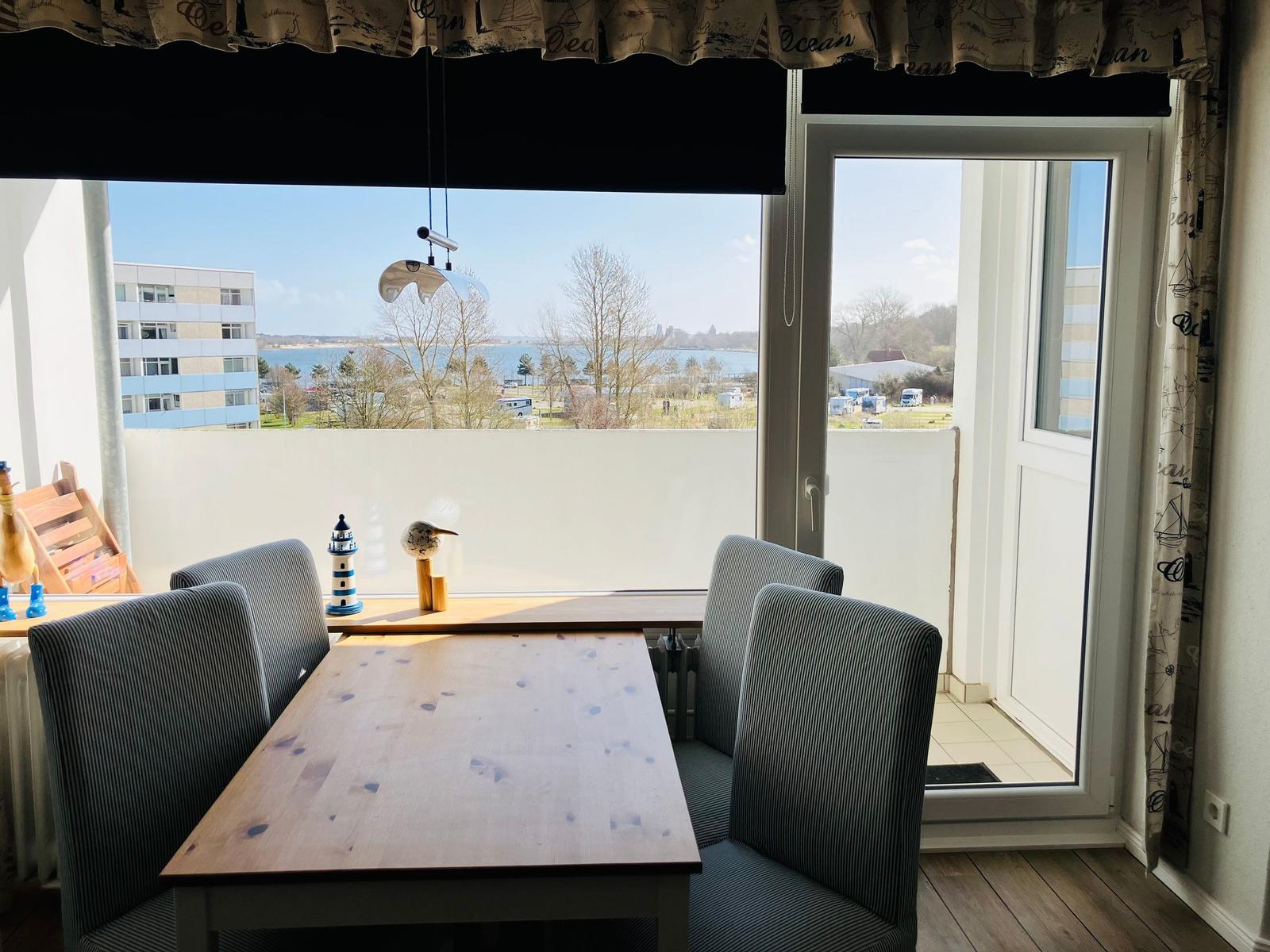 Esszimmer mit Tisch und Stühlen. Blick auf Wasser und Gebäude durch Fenster.