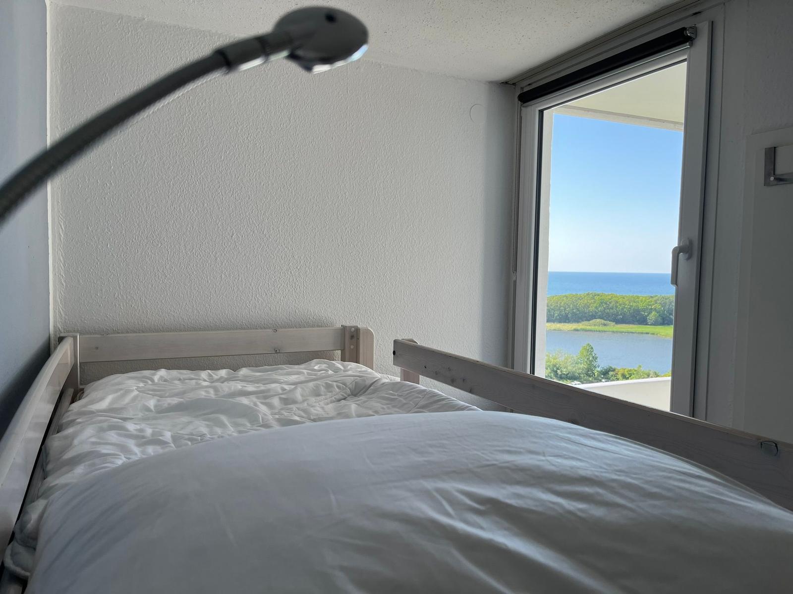 Schlafzimmer mit Blick auf See und Wald durch geöffnete Tür