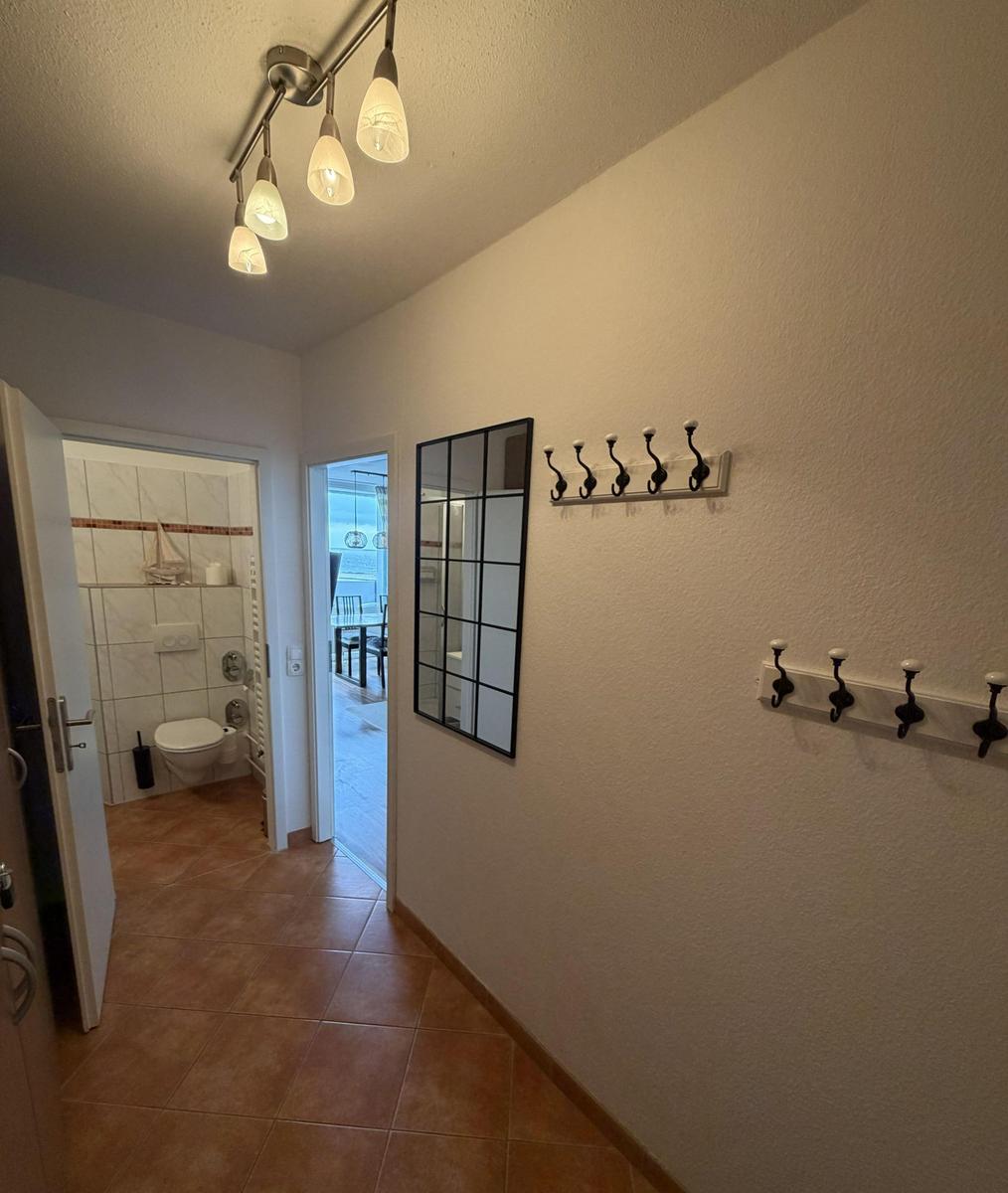 Flur mit Garderobe, Spiegel und Blick in Bad und Terrasse.