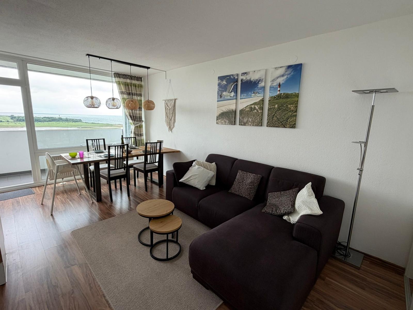 Wohn- und Essbereich mit Blick aufs Meer und Strand. Sofa, Tisch und Stühle.