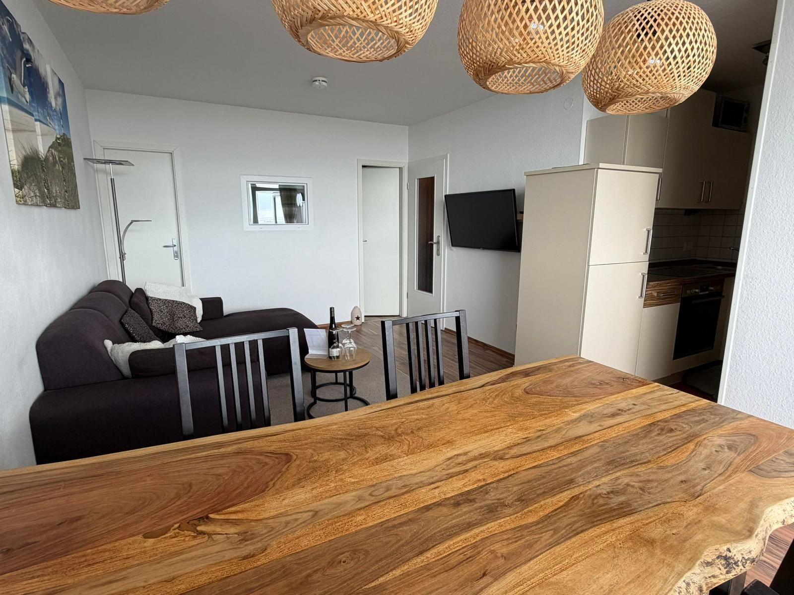 Wohn- und Essbereich mit Holztisch, Sofa und Küchenbereich