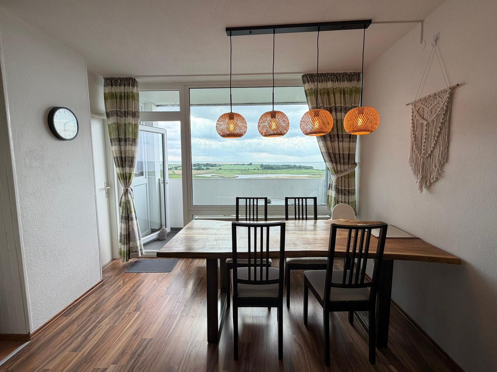 Esszimmer mit Tisch, Stühlen und Blick auf Landschaft.