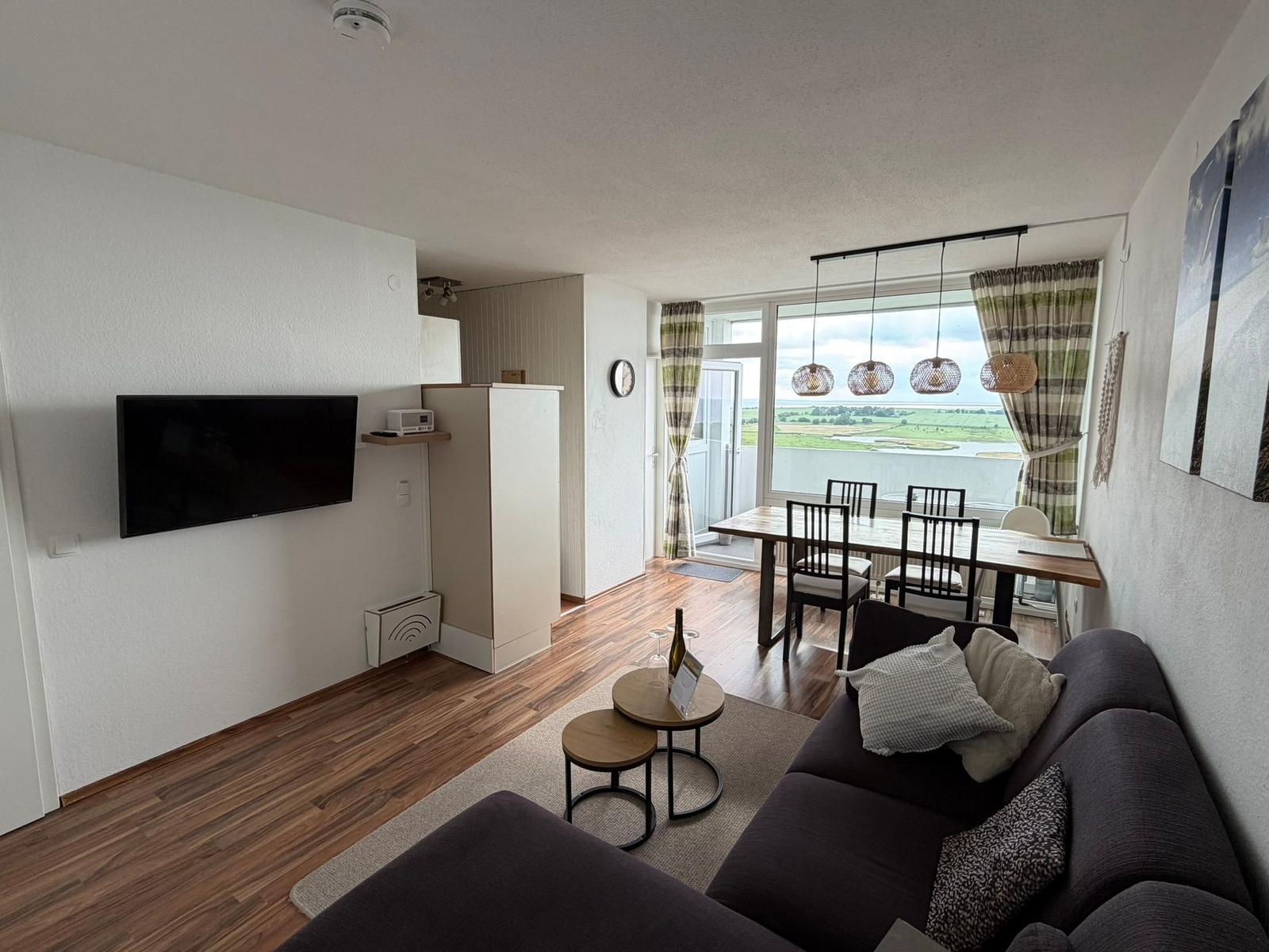 Wohn- und Essbereich mit TV, Sofa und Blick auf Wasser