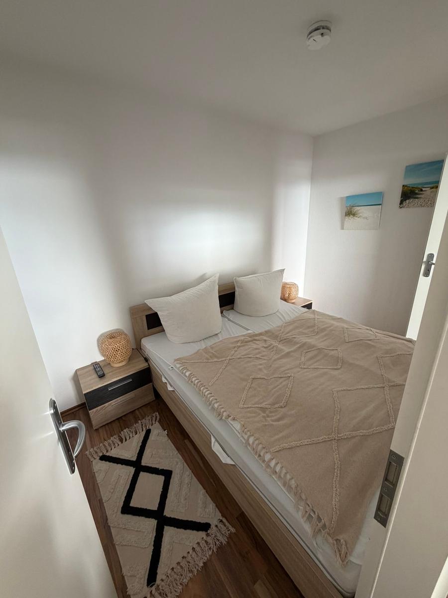 Schlafzimmer mit Bett, Nachttisch und Wandbildern.