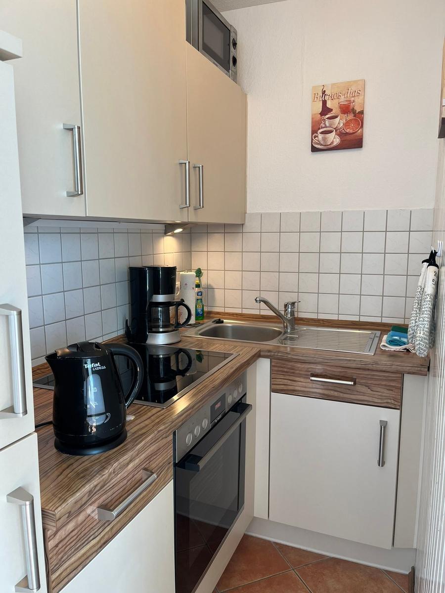 Küche mit Arbeitsfläche, Spüle, Kühlschrank und Kochfeld.