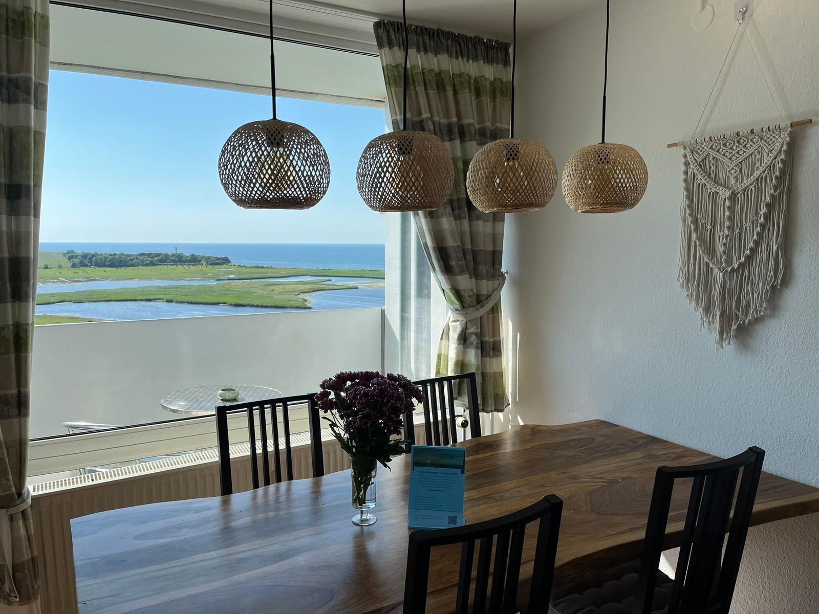 Esszimmer mit Tisch, Stühlen und Blick aufs Meer.