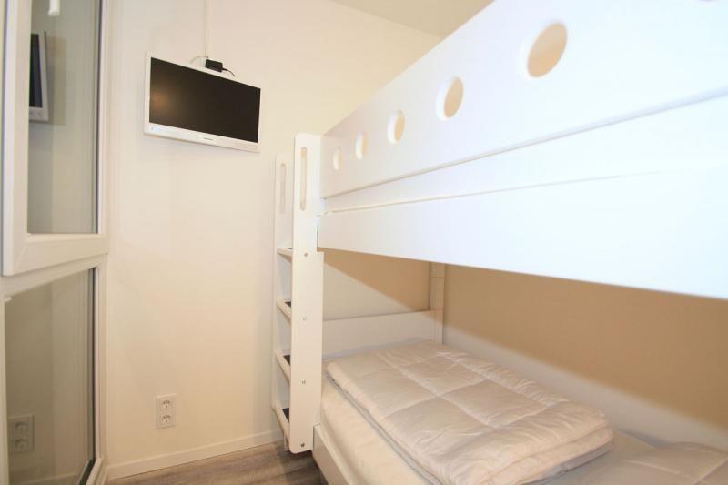 Room with bunk bed, wall-mounted TV, and ladder.