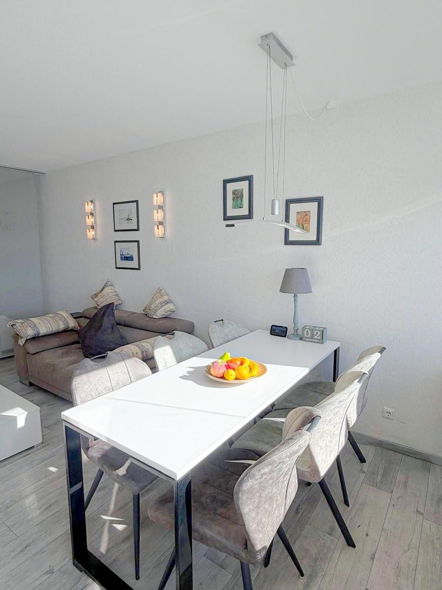 Essbereich mit Tisch und Stühlen, daneben Wohnbereich mit Sofa und Wandbildern.