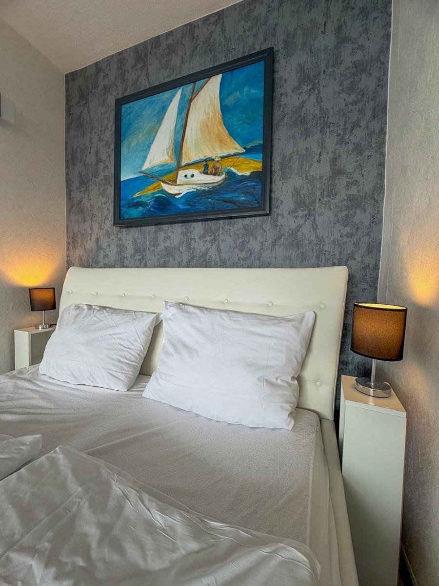 Schlafzimmer mit Bett, Nachttischen und Wandbild mit Segelboot.