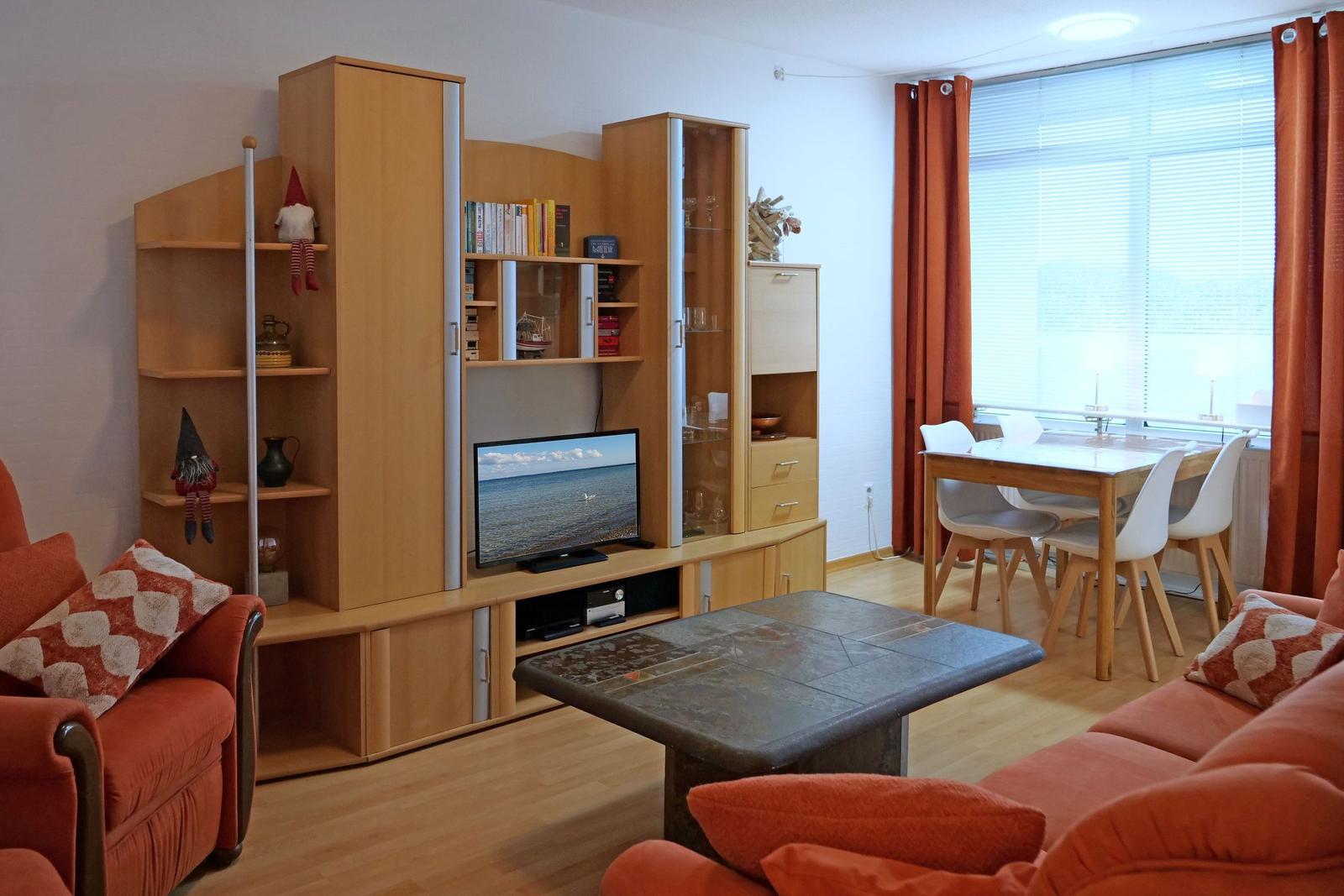 Living and dining area with wooden furniture, TV, and window with curtains.