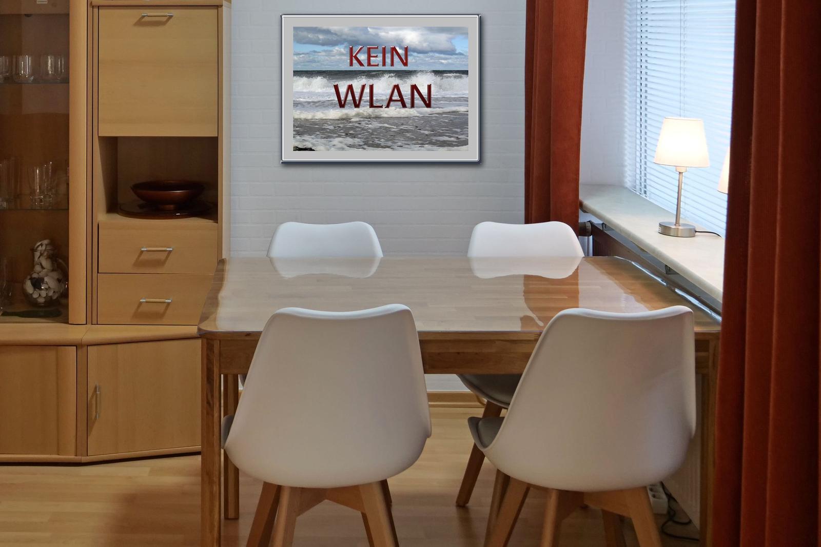 Dining room with wooden table, white chairs, and wall picture with sea and text.