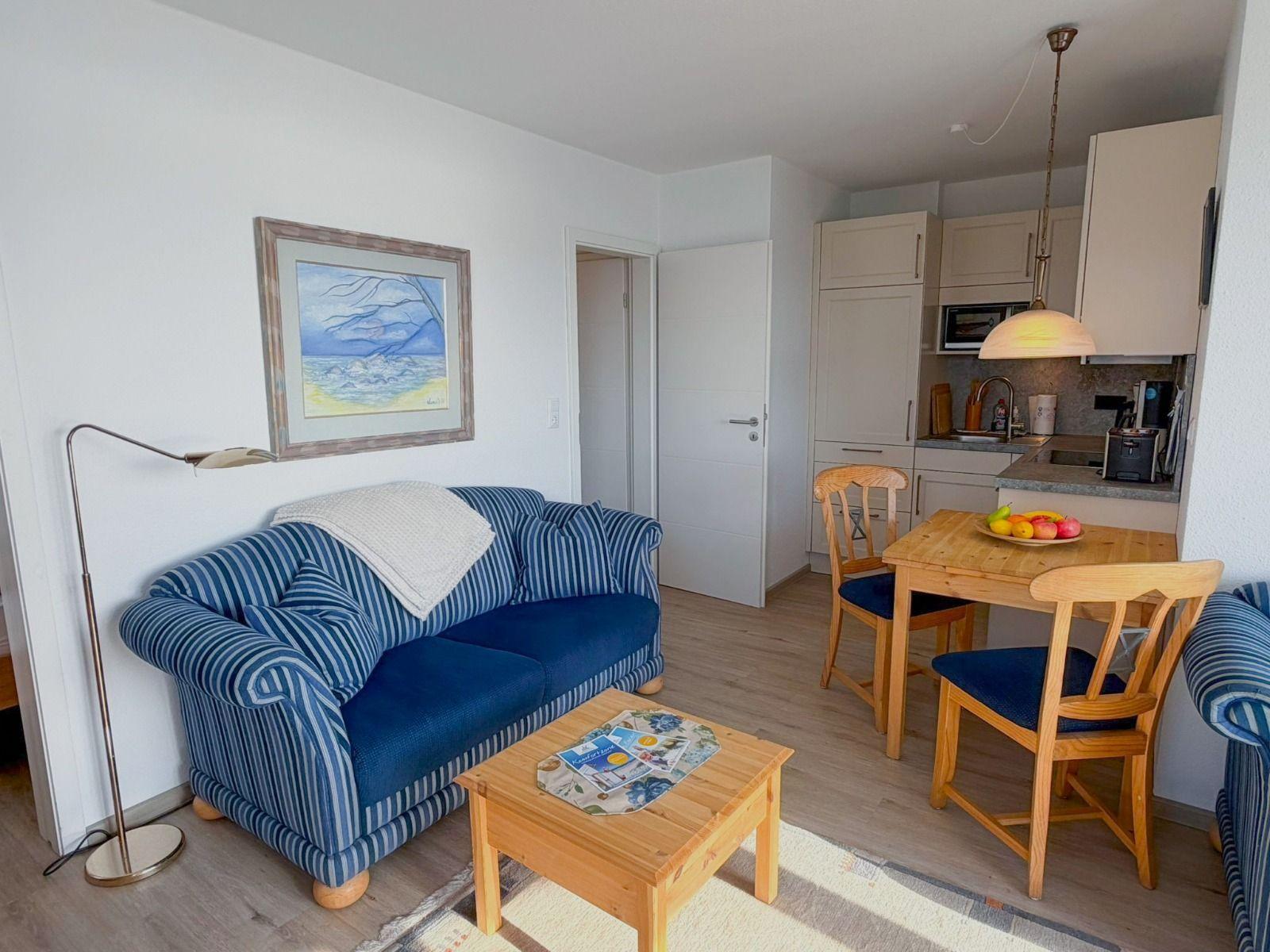 Living and kitchen area with sofa, dining table, and kitchen cabinets.