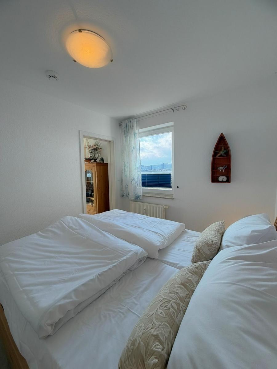Bedroom with double bed, window overlooking water, and wall shelf in boat shape.