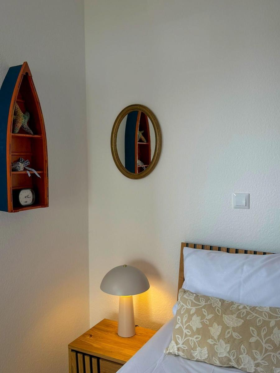 Bedroom with bed, nightstand, and wall shelf shaped like a boat.