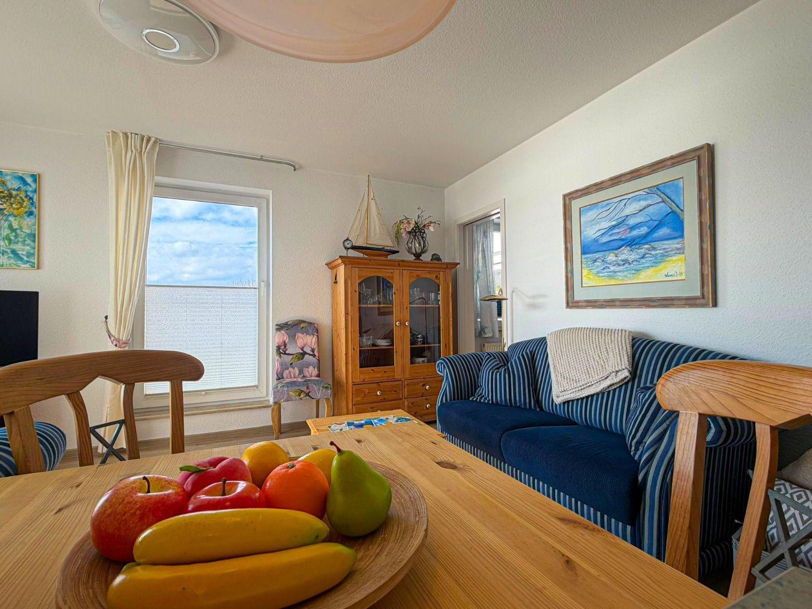 Dining area with wooden table, blue striped sofa, and kitchen wall.