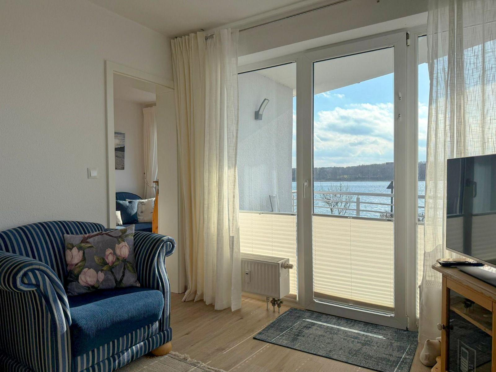 Living room with view of the lake through glass door and balcony