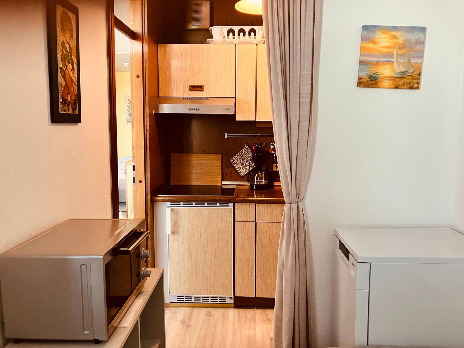 Kitchen with wooden cabinets, microwave, and washing machine.