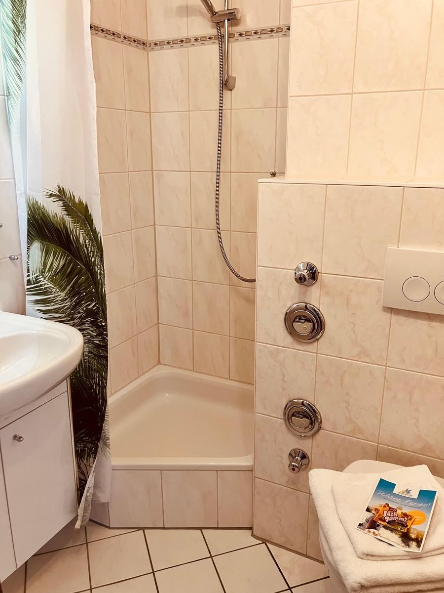 Bathroom with shower, sink, and toilet. Tiled walls and floor.