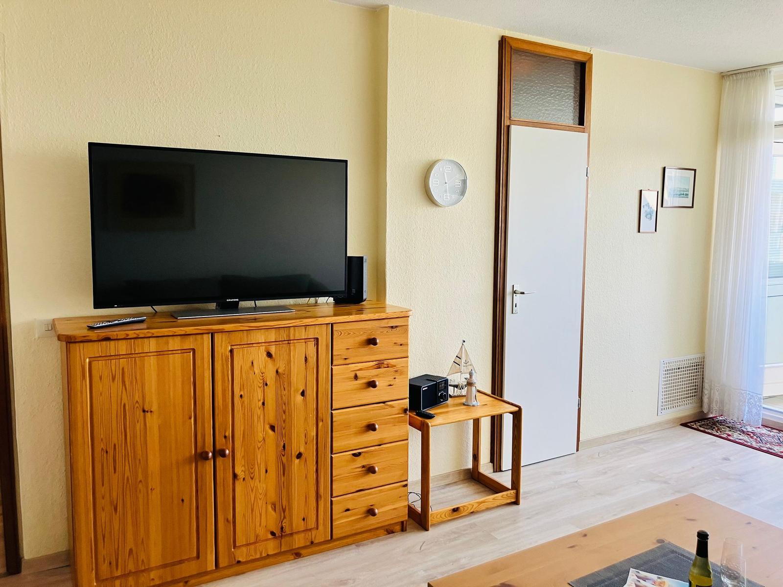 Living room with wooden cabinet, TV, and door