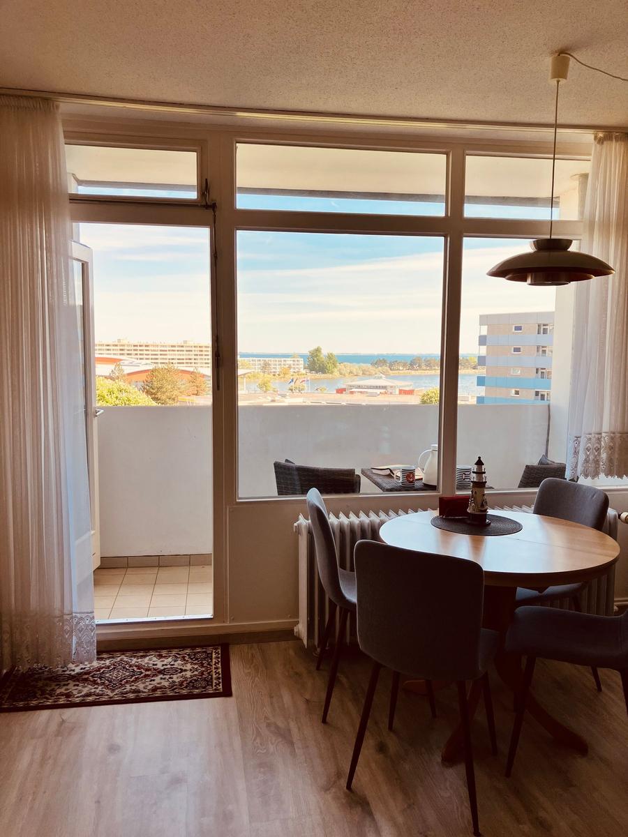 Dining room with harbor and sea view. Round table, chairs, balcony with seating area.