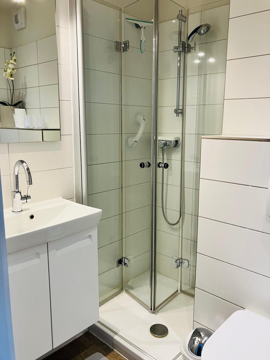 Badezimmer mit Dusche, Waschbecken und Spiegel