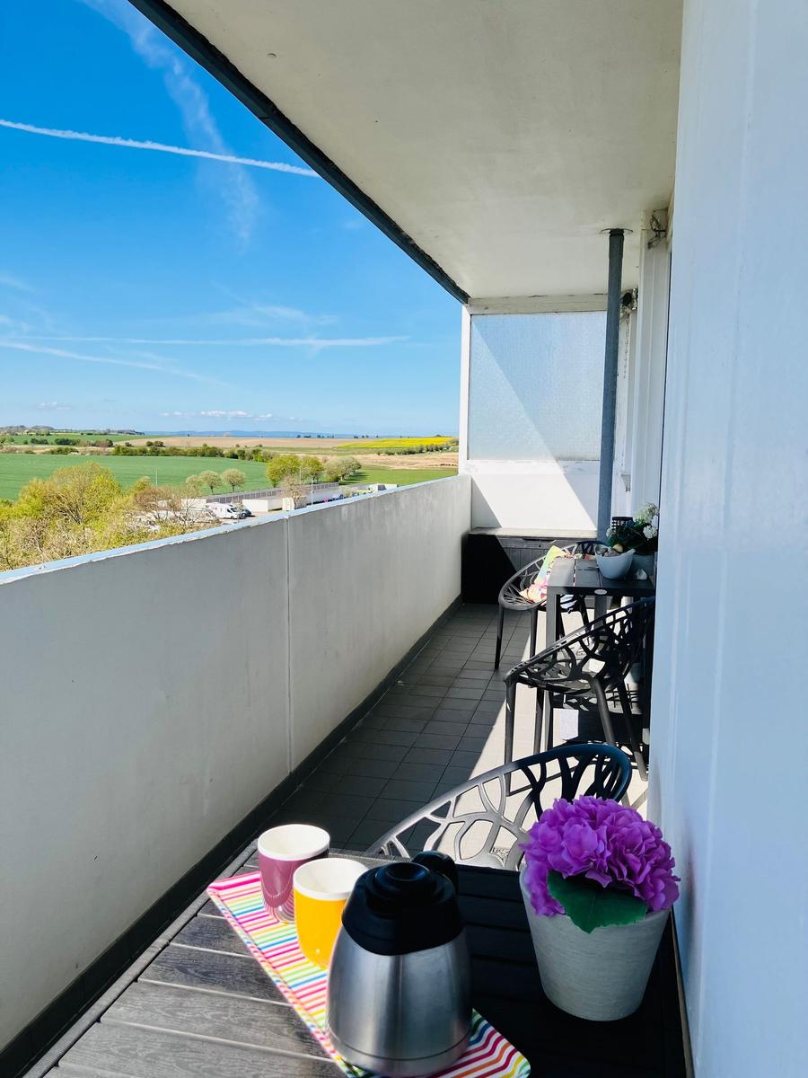 Balkon mit Tisch, Stühlen und Blick auf grüne Landschaft.