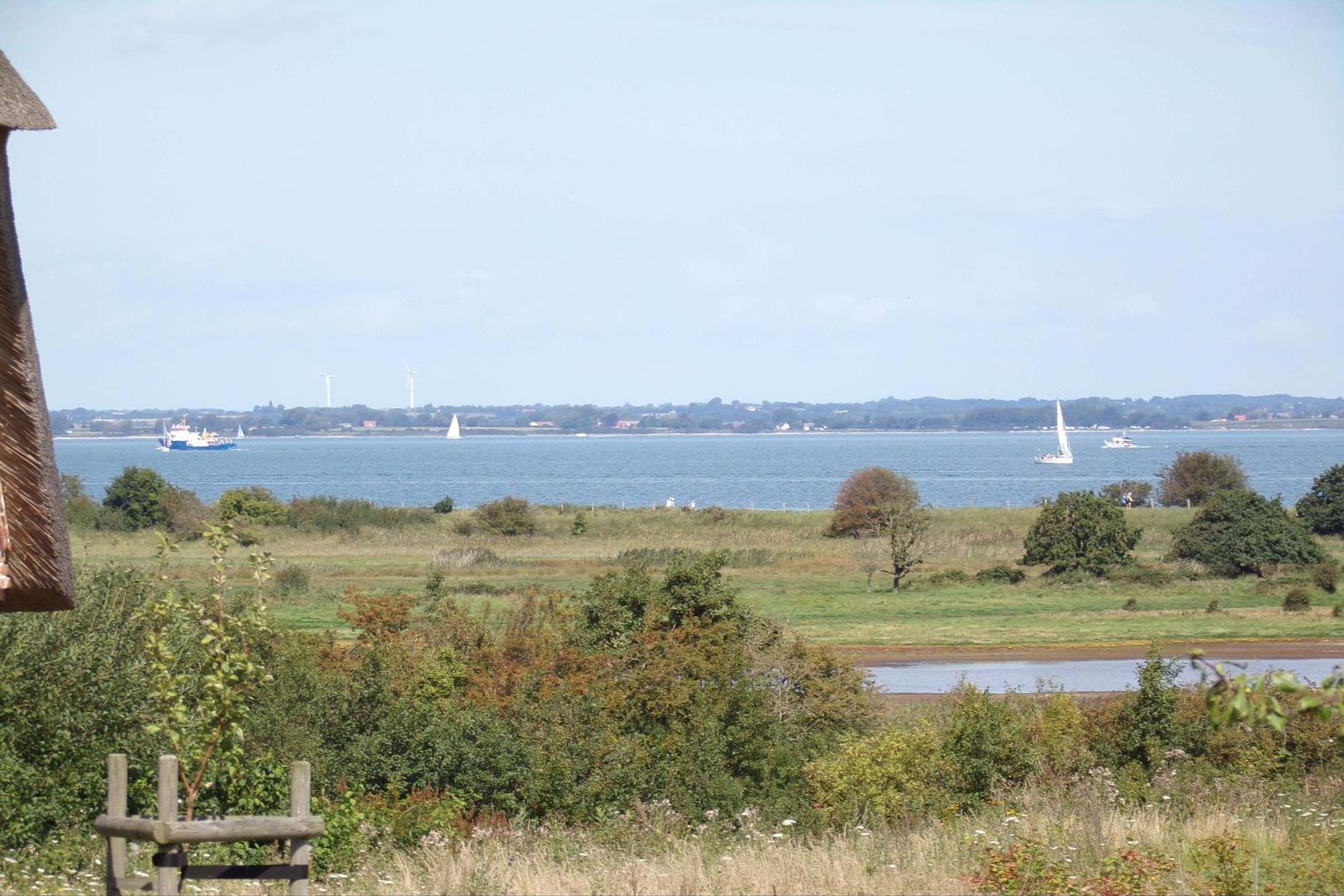 Weitläufiger Blick aufs Wasser mit Booten und Windmühlen im Hintergrund.