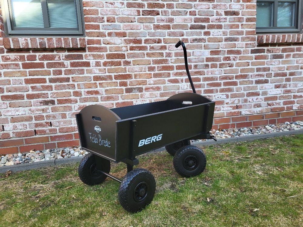 Black wagon with four wheels in front of brick wall
