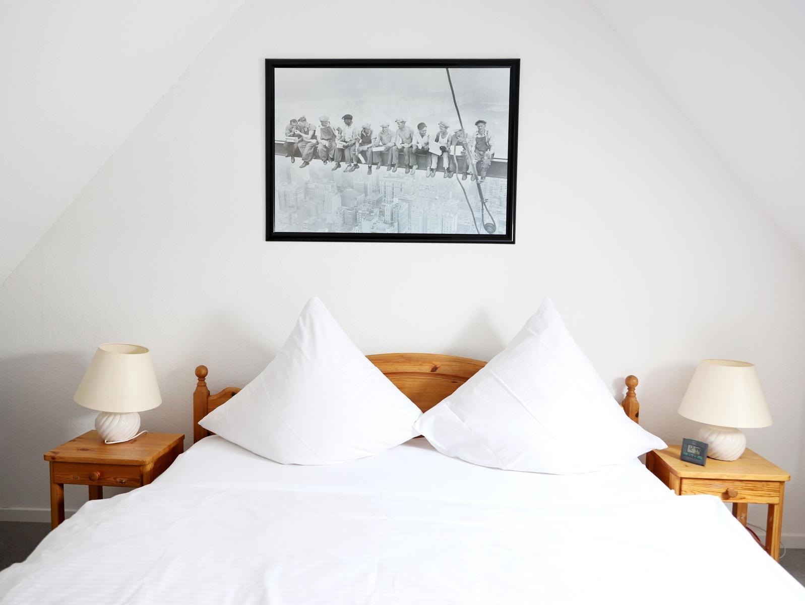 Schlafzimmer mit Bett, zwei Nachttischen und Wandbild.