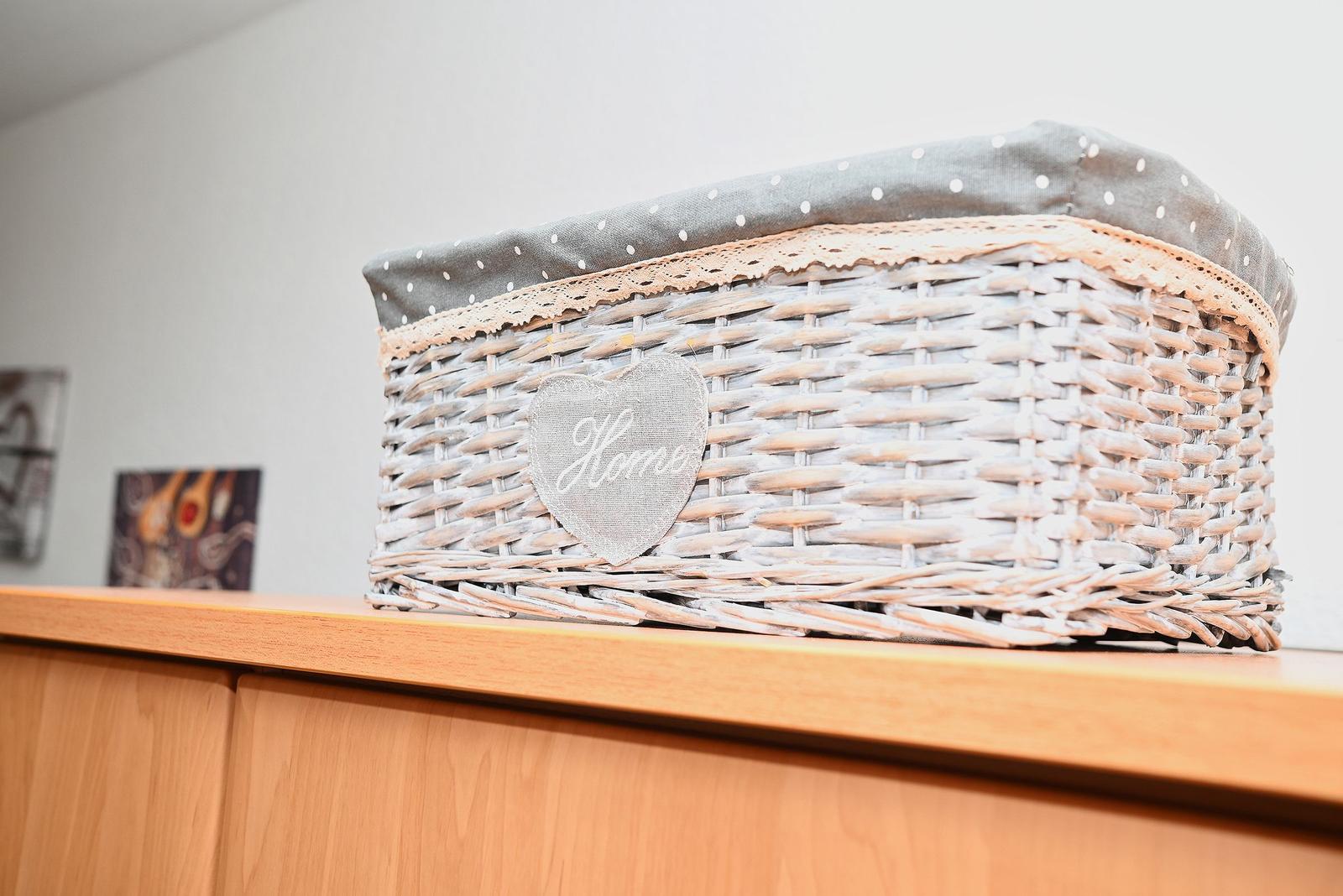 Ein geflochtener Korb mit Herz-Aufkleber steht auf einem Holzregal.