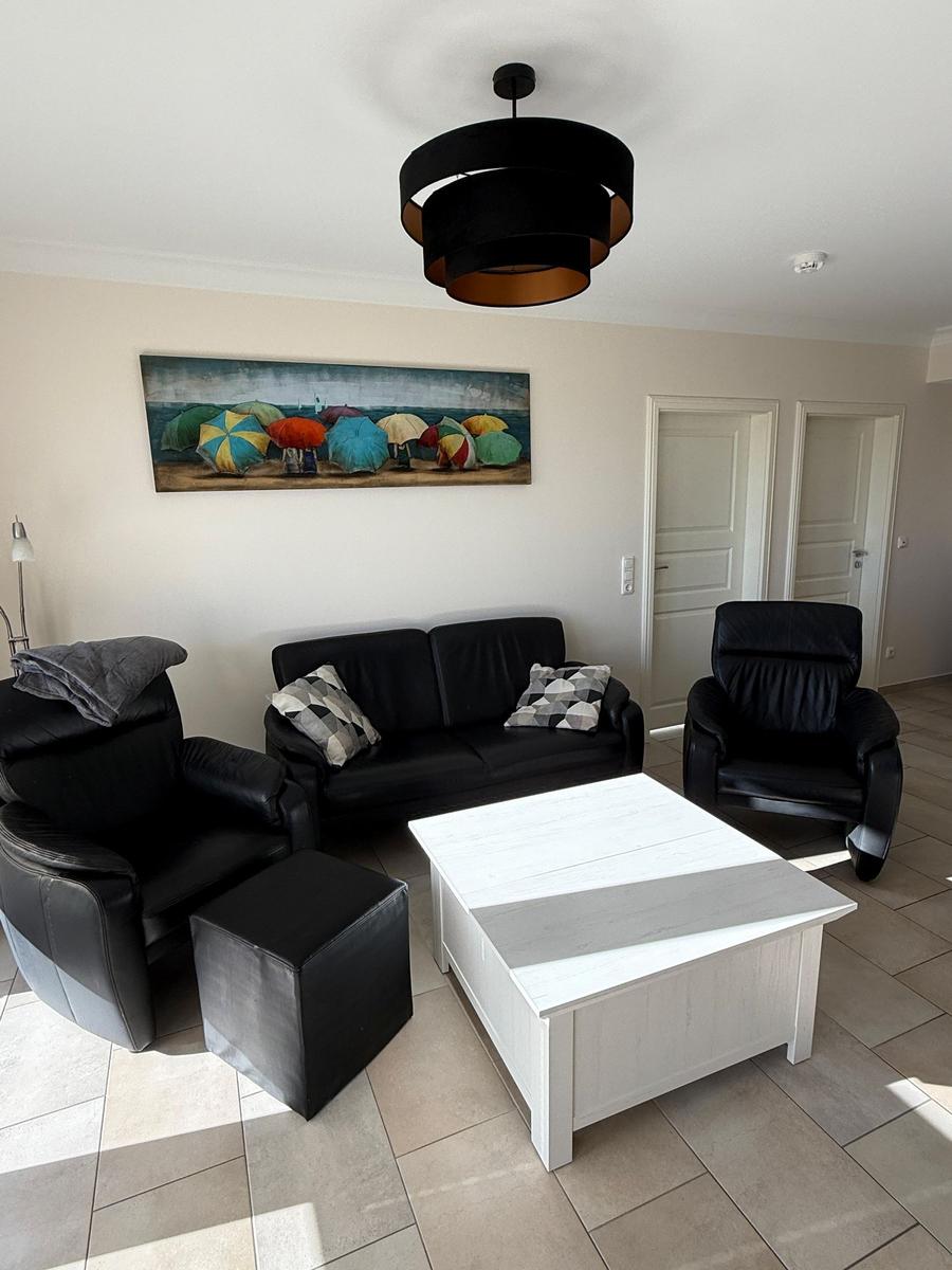 Living room with black seating, white table, and wall art with colorful umbrellas.