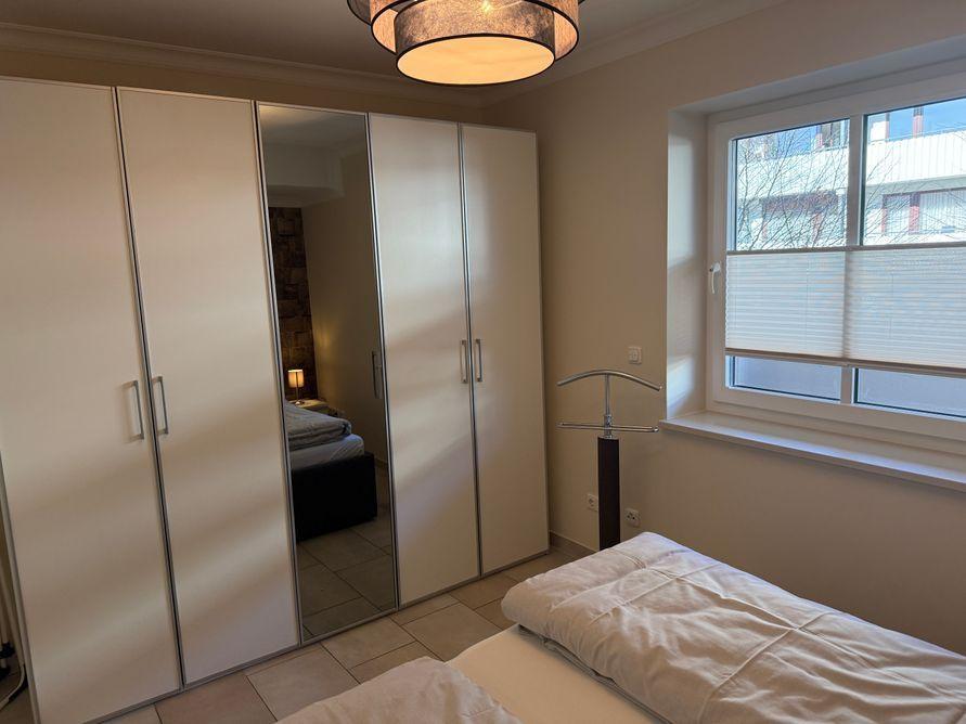 Bedroom with wardrobe, bed, and window with blinds.