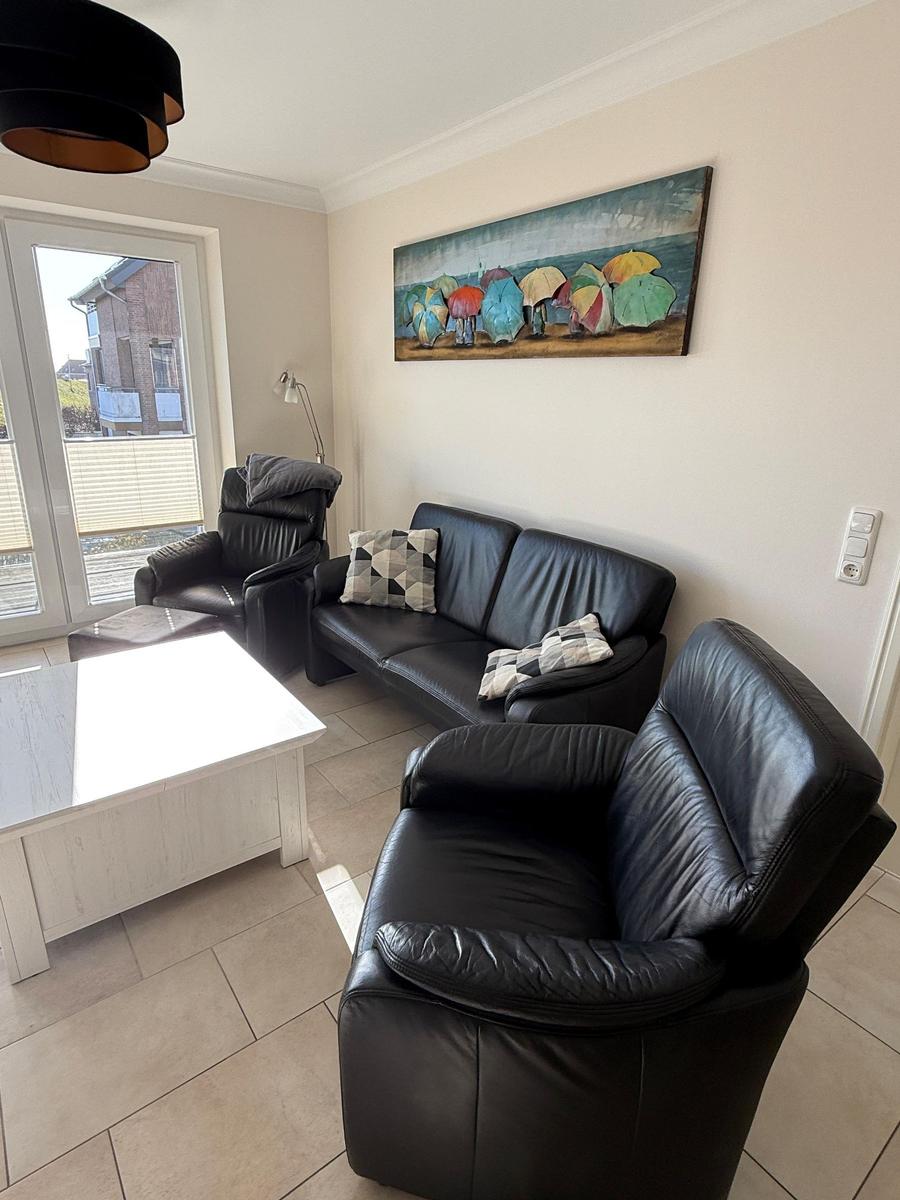 Living room with black leather furniture, white table, and wall art with umbrellas.