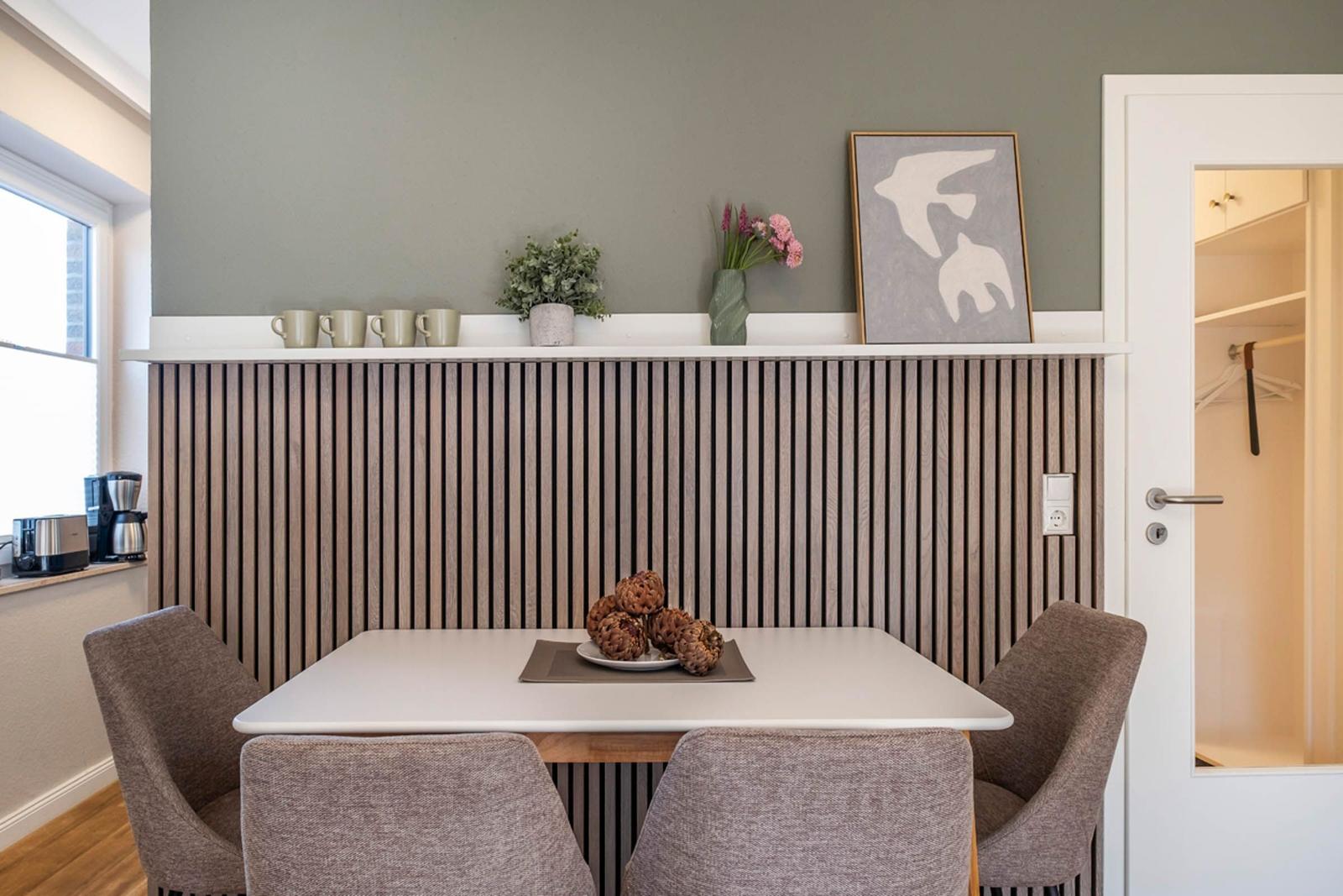 Essbereich mit Tisch, vier Stühlen und Holzpaneelen an der Wand.