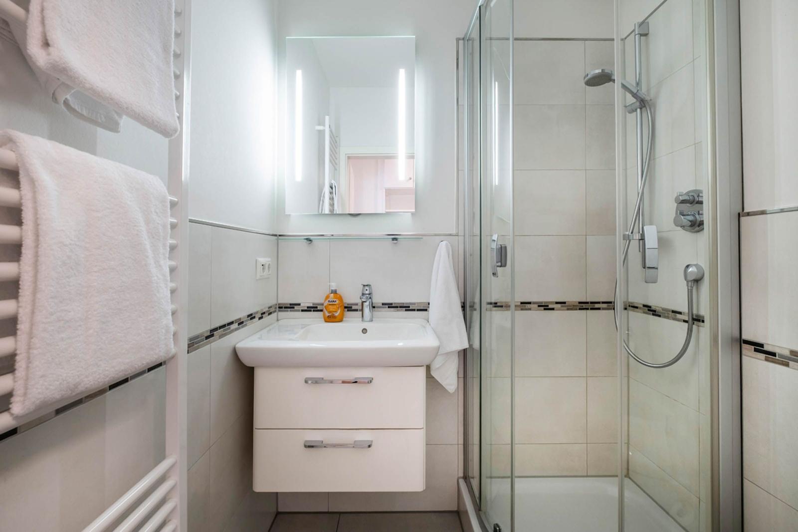Badezimmer mit Dusche, Waschbecken und Handtuchhalter.