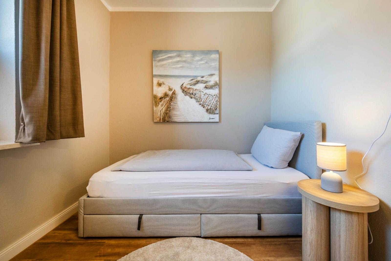 Schlafzimmer mit Bett, Nachttisch und Wandbild.