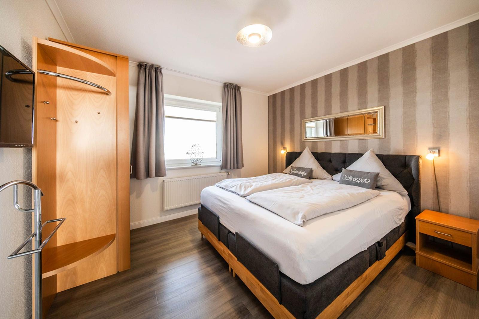 Bedroom with double bed, wardrobe, and window with curtains.