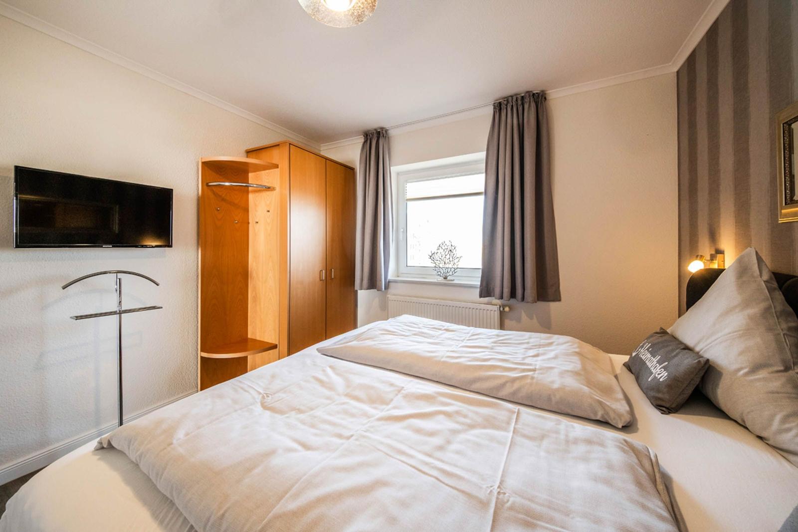 Bedroom with double bed, wardrobe, window, and wall-mounted TV.