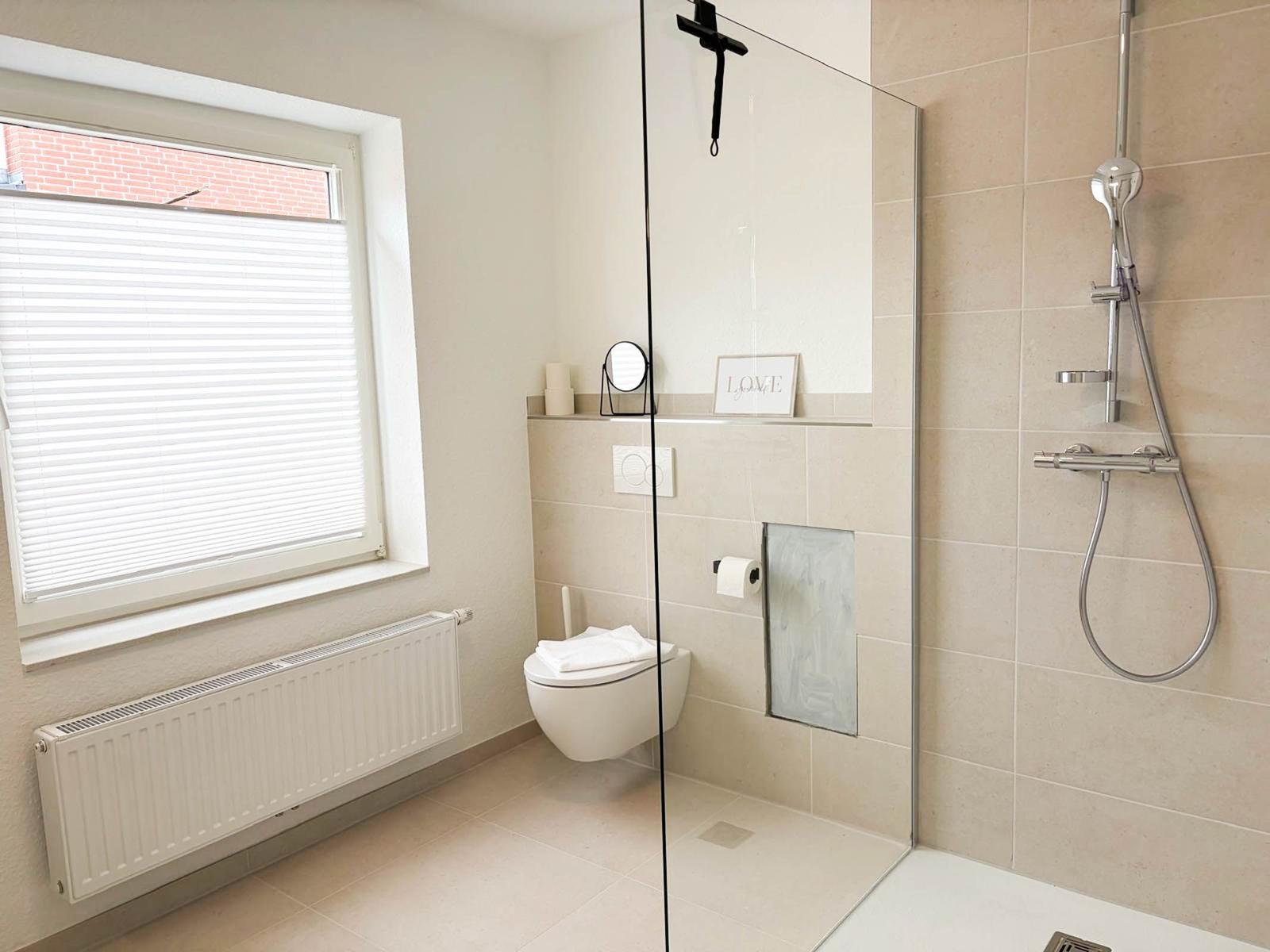 Bad mit Dusche, Toilette und Fenster mit Jalousie.