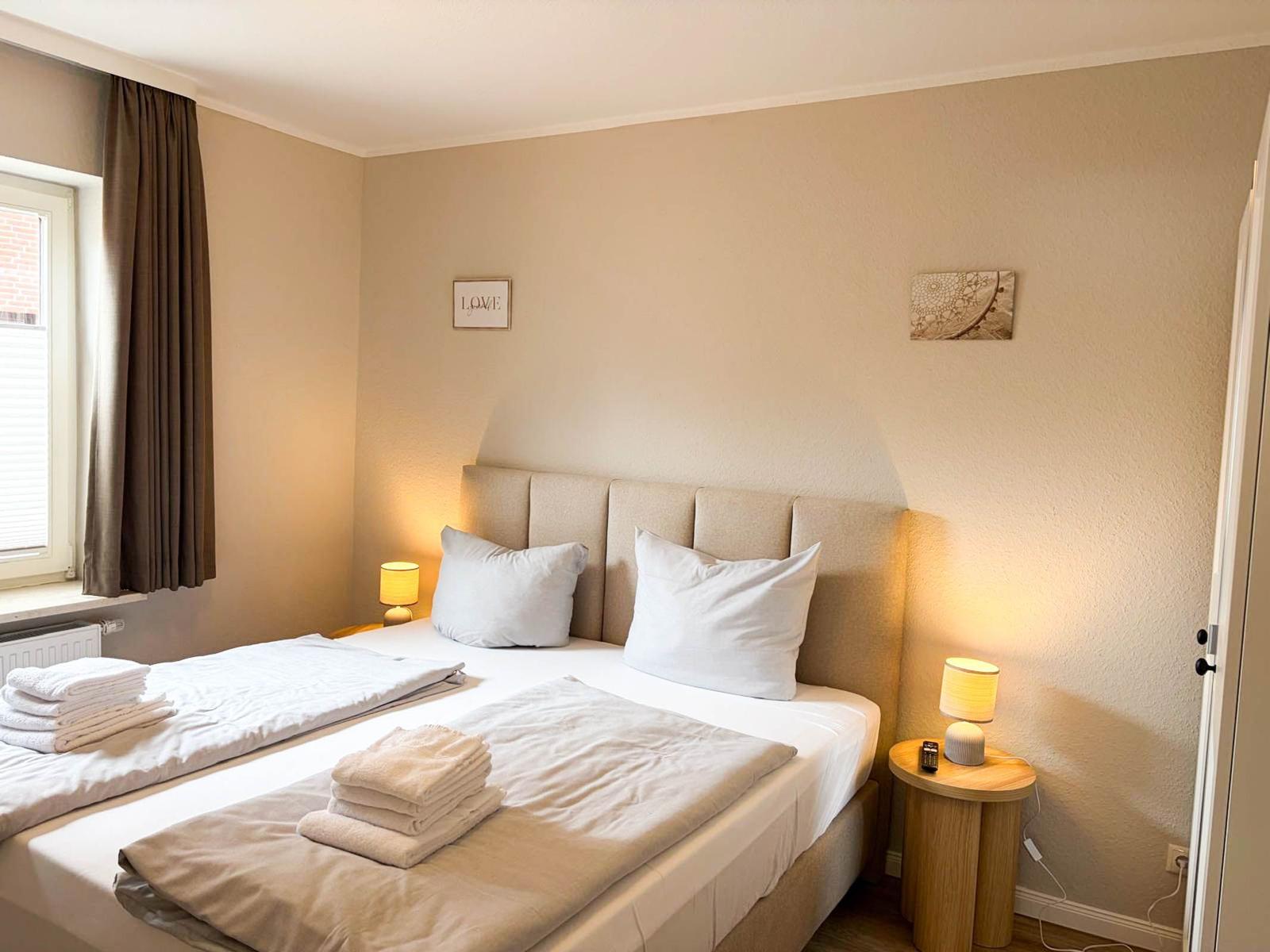 A bedroom with a bed, two nightstands, and a window.