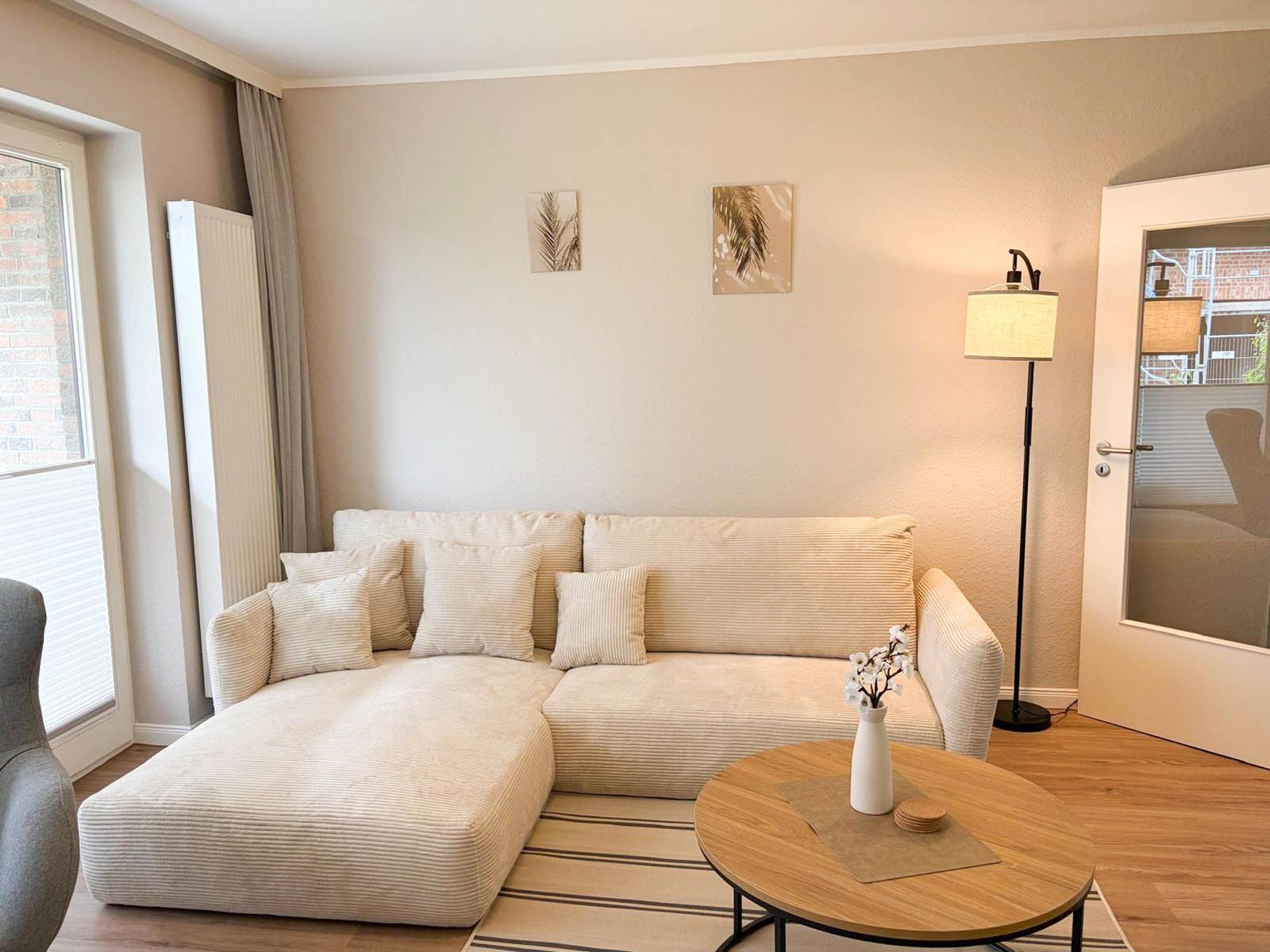 Living room with corner sofa, round table, and floor lamp.