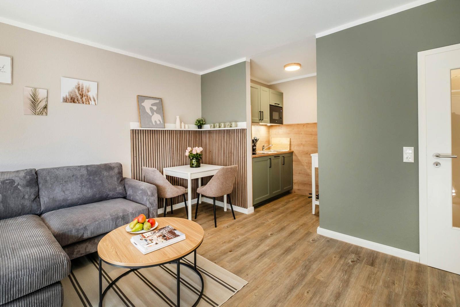 Wohnbereich mit Sofa, Esstisch und Küche im Hintergrund.