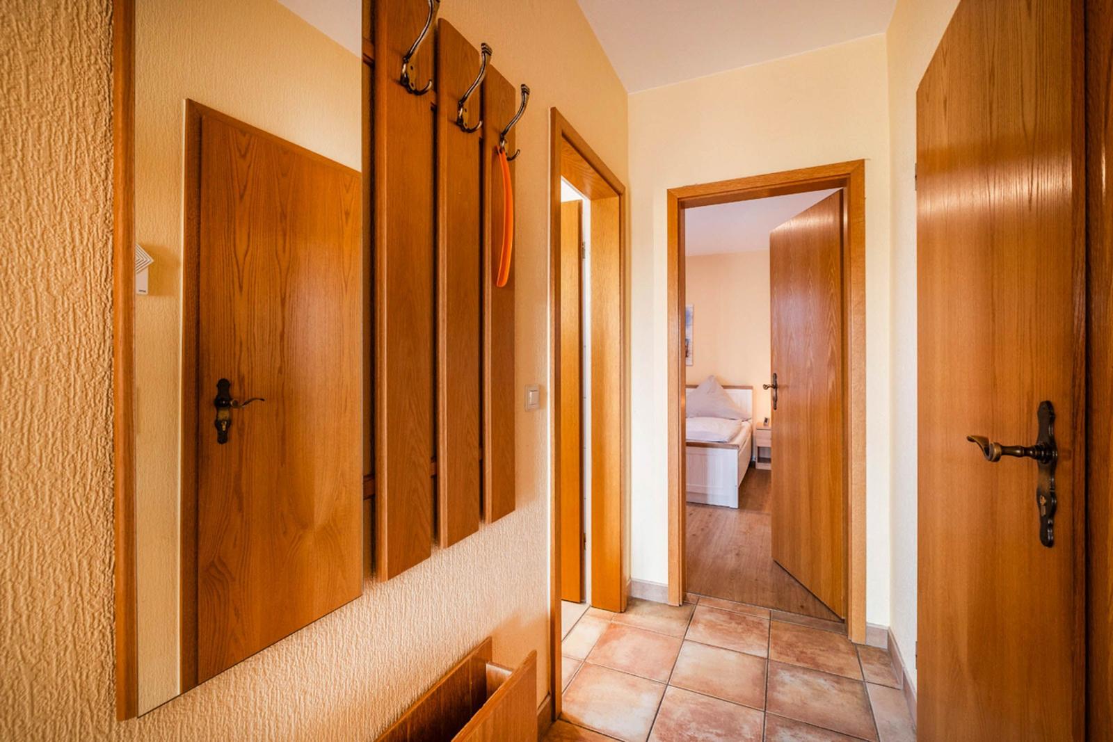 Flur mit Holztüren, Garderobenstange und Blick in Schlafzimmer