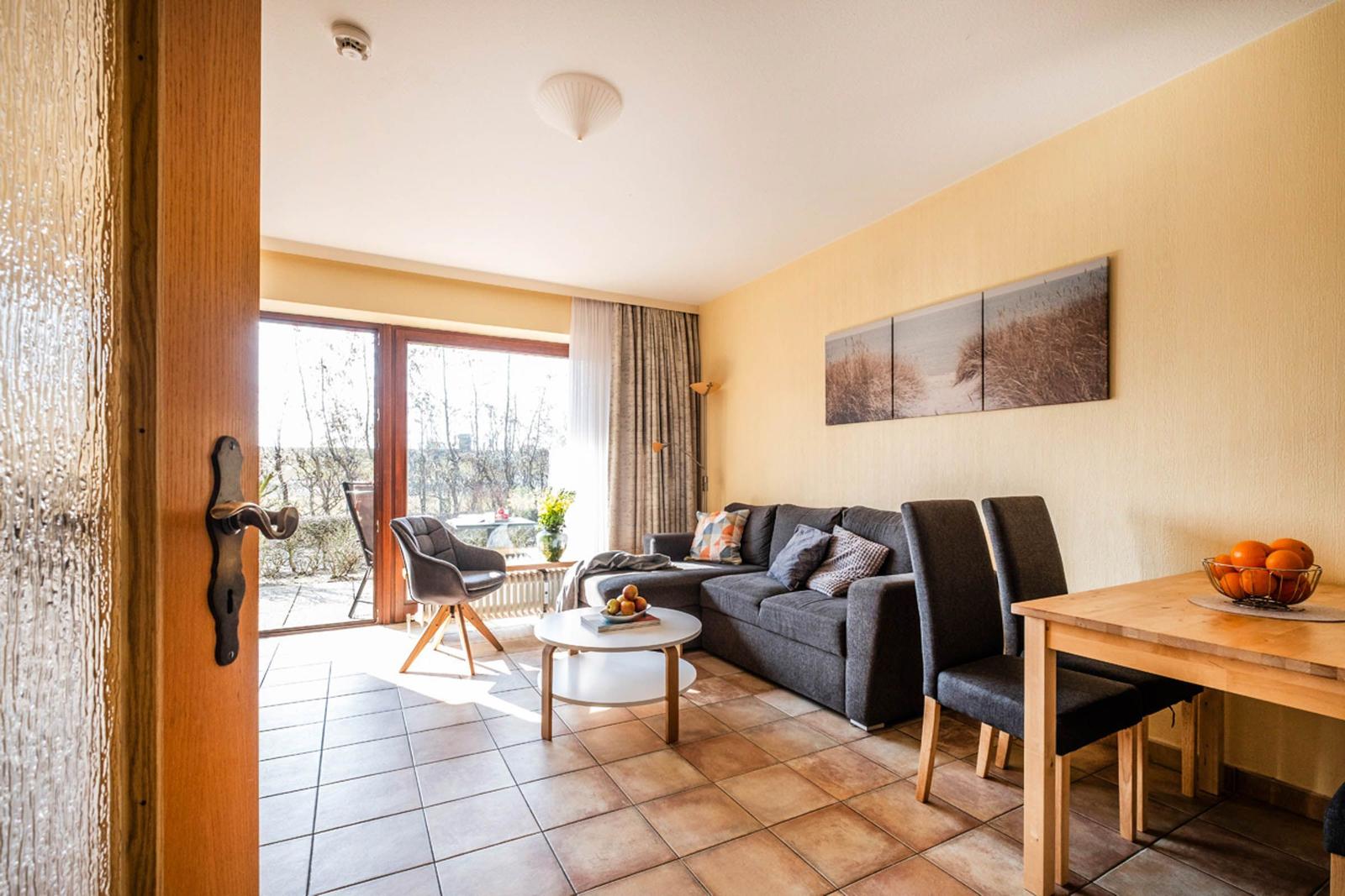 Wohn- und Essbereich mit Sofa, Tisch und Blick auf Balkon.