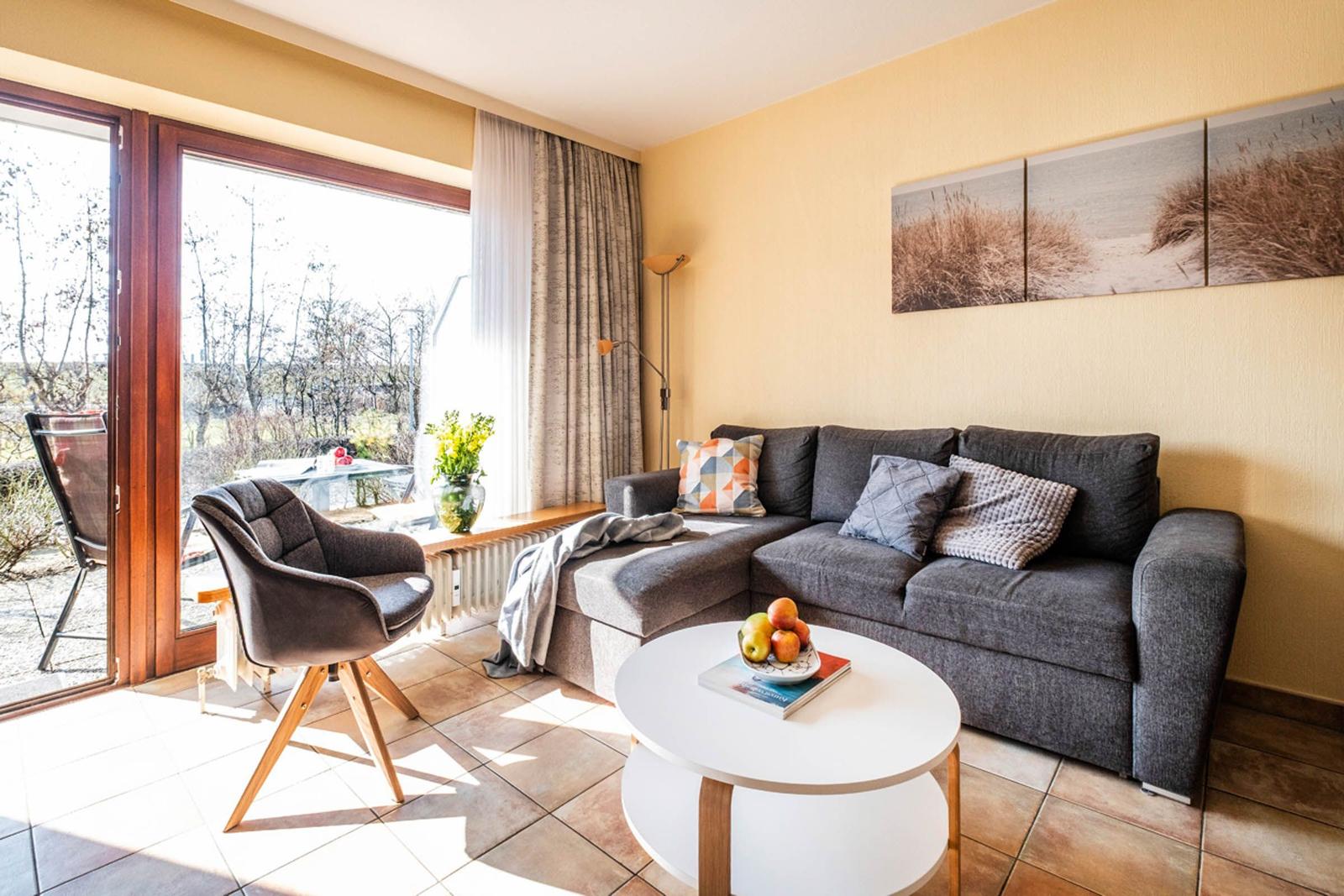 Wohnzimmer mit Sofa, Sitzgelegenheit und Blick auf Balkon.