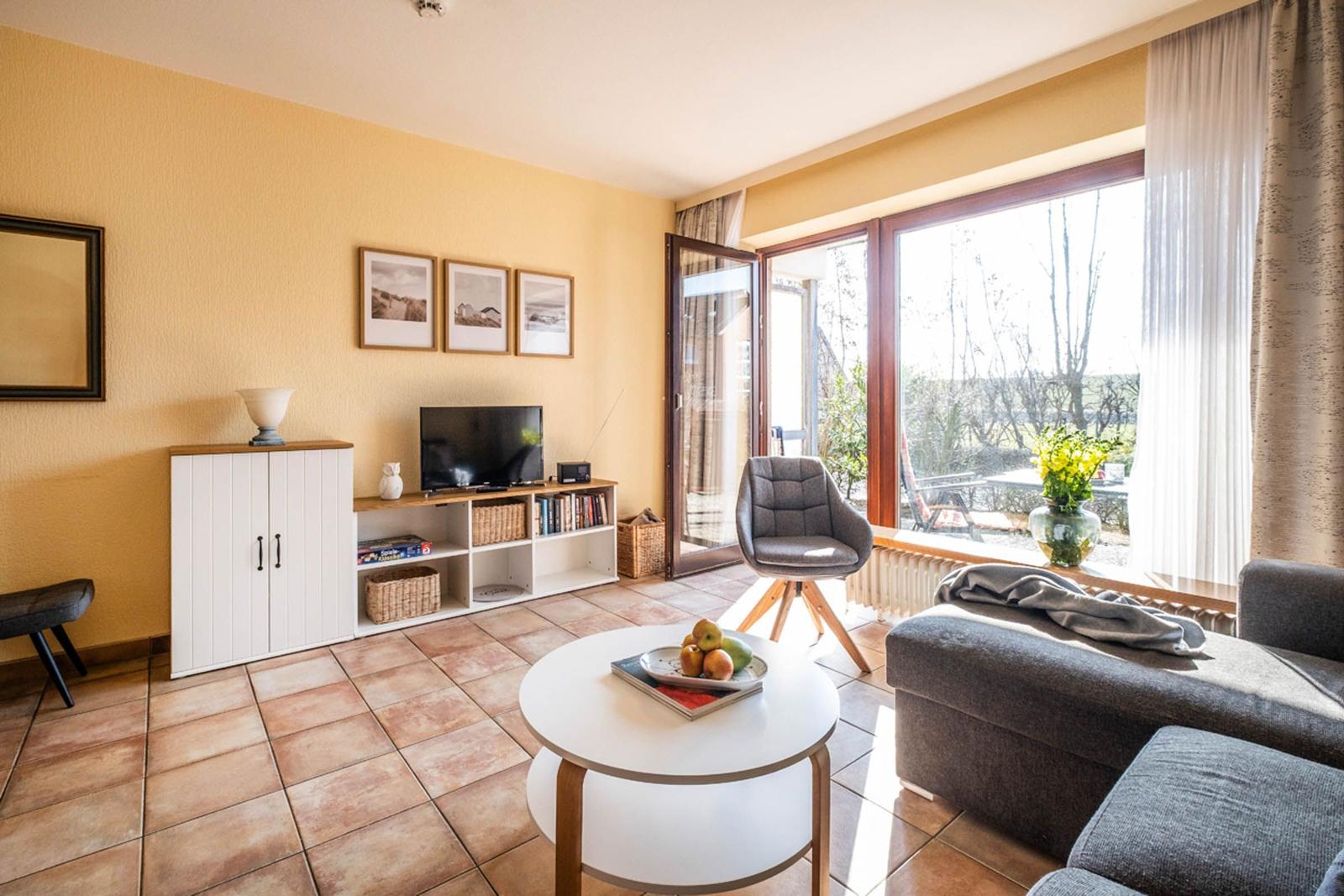 Wohnzimmer mit TV, Sofa und Terrassentür. Fensterblick auf Garten.