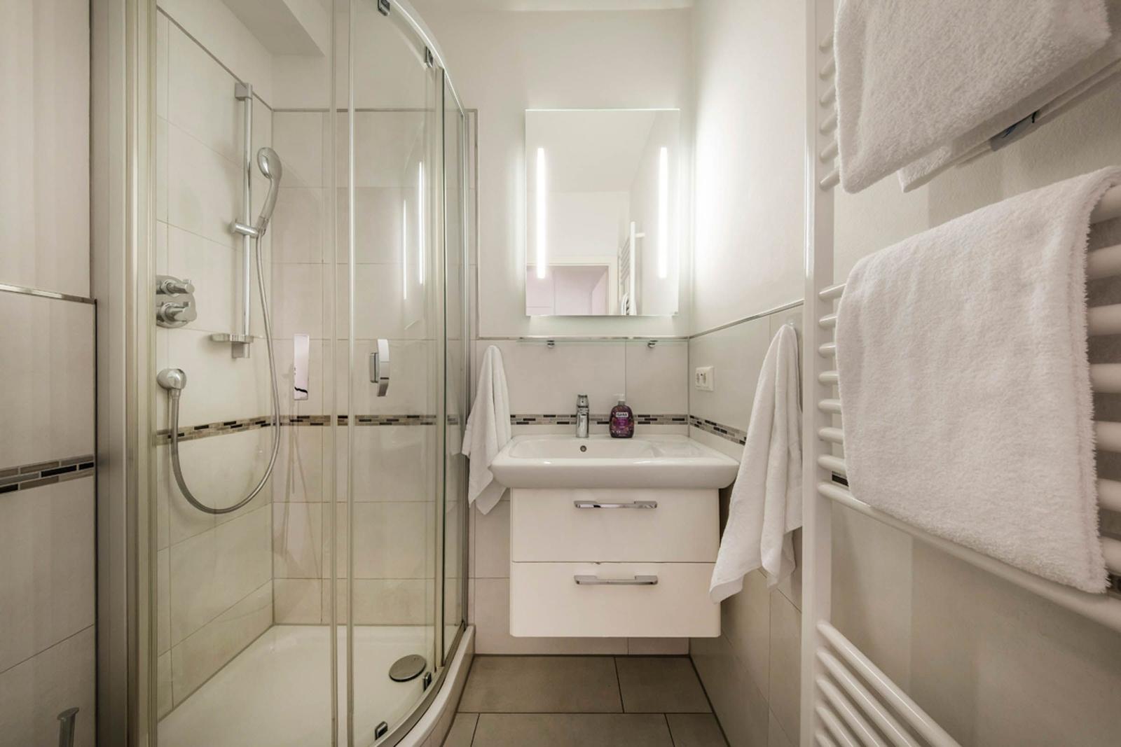 Badezimmer mit Dusche, Waschbecken und Handtuchhalter
